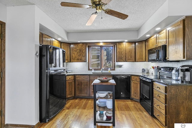 kitchen with sink, decorative backsplash, black appliances, and light hardwood / wood-style floors