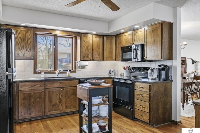 kitchen featuring sink, light hardwood / wood-style flooring, ceiling fan, backsplash, and black appliances