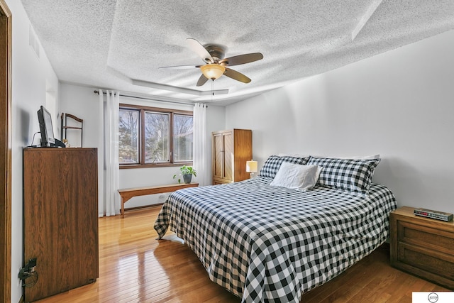 bedroom featuring ceiling fan, a textured ceiling, and light hardwood / wood-style floors