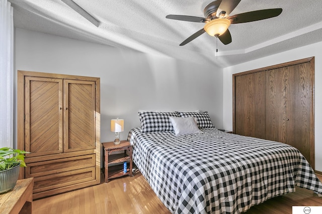 bedroom featuring ceiling fan, light hardwood / wood-style floors, a closet, and a textured ceiling