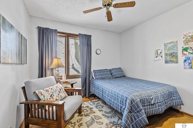 bedroom with wood-type flooring, ceiling fan, and a textured ceiling