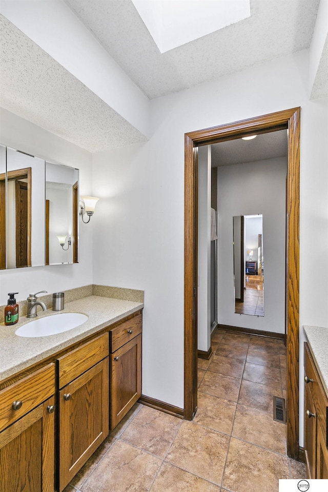 bathroom with vanity, a textured ceiling, and a skylight