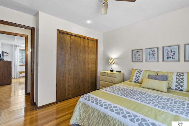 bedroom with wood-type flooring, ceiling fan, a textured ceiling, and a closet