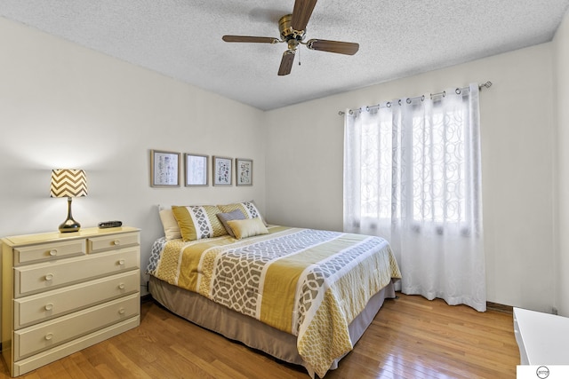 bedroom with ceiling fan, a textured ceiling, and light wood-type flooring