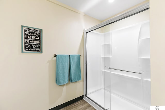 bathroom with a shower with door and wood-type flooring