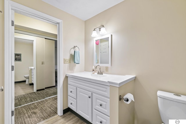 bathroom with vanity, wood-type flooring, and toilet