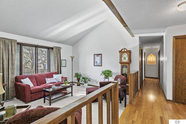 living room featuring vaulted ceiling, a textured ceiling, and light hardwood / wood-style floors