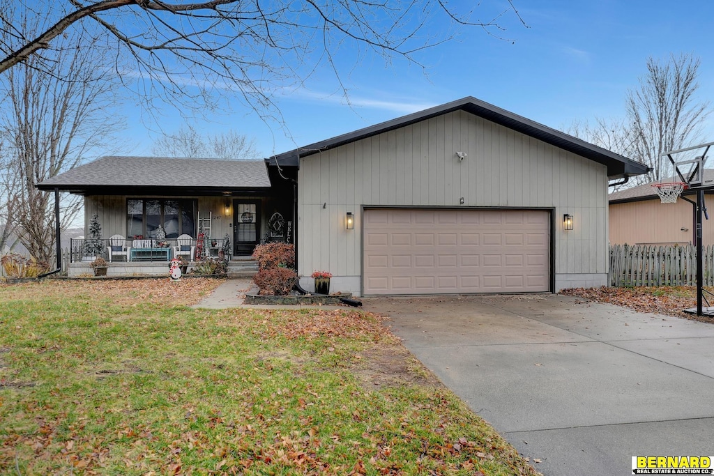 single story home featuring a garage, covered porch, and a front lawn