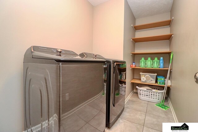 laundry room featuring light tile patterned floors, a textured ceiling, and washing machine and clothes dryer