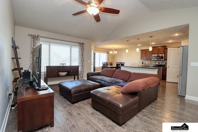 living room with hardwood / wood-style flooring, vaulted ceiling, sink, and ceiling fan with notable chandelier