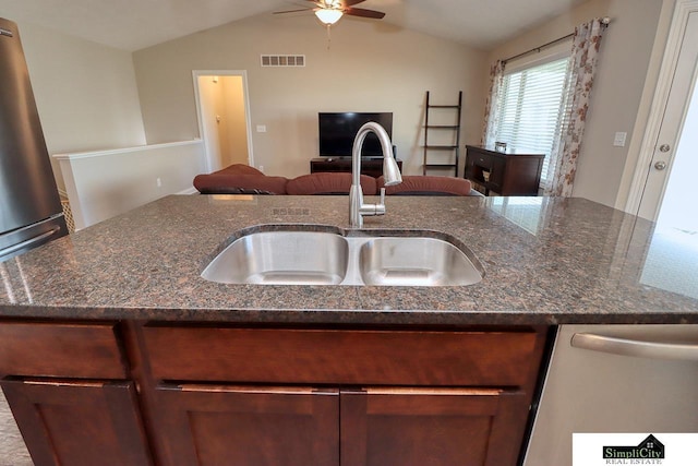 kitchen with lofted ceiling, sink, dishwasher, ceiling fan, and dark stone countertops