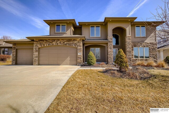 prairie-style home with an attached garage, stone siding, driveway, and stucco siding