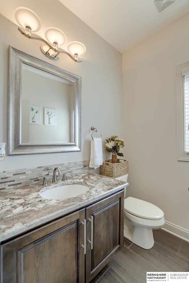 bathroom with visible vents, toilet, vanity, and baseboards