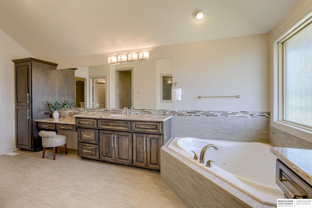 full bathroom with vanity, vaulted ceiling, and a whirlpool tub