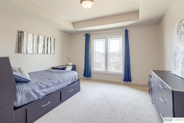 bedroom with a raised ceiling, baseboards, and light carpet