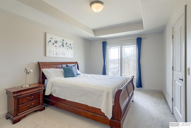 bedroom featuring light carpet, baseboards, and a tray ceiling