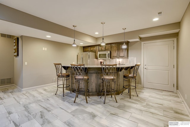 kitchen featuring a peninsula, a breakfast bar area, visible vents, and stainless steel appliances