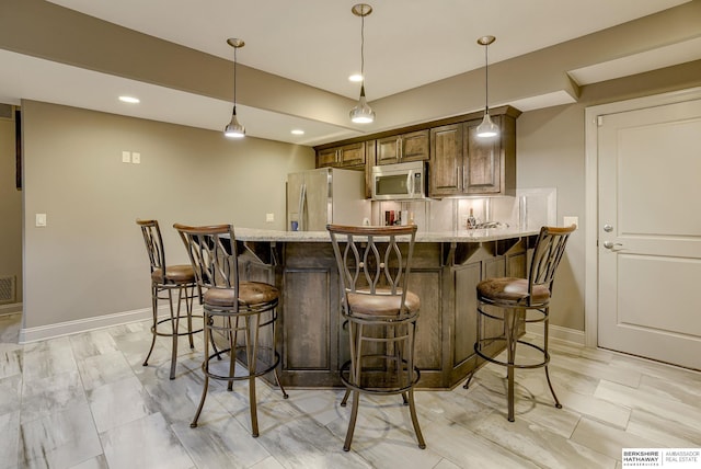 interior space featuring light stone countertops, baseboards, a breakfast bar, a peninsula, and appliances with stainless steel finishes