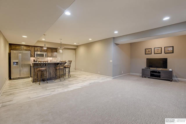 kitchen with a breakfast bar, recessed lighting, stainless steel appliances, light colored carpet, and open floor plan