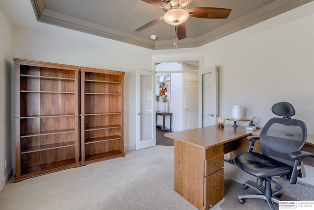 office space with a raised ceiling, light colored carpet, and crown molding