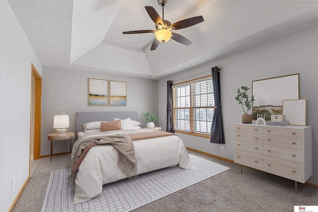 bedroom featuring ceiling fan, a raised ceiling, a textured ceiling, and carpet flooring