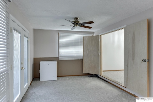 spare room with light carpet, ceiling fan, and a textured ceiling