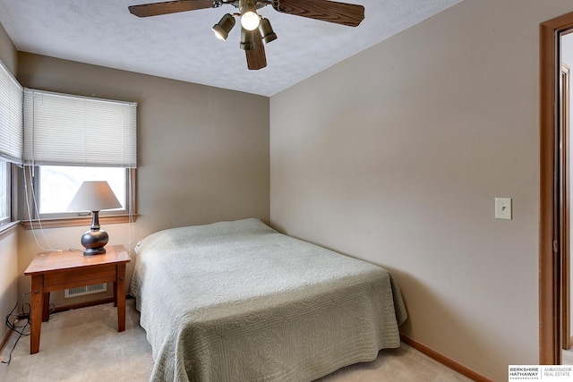 carpeted bedroom featuring ceiling fan and a textured ceiling