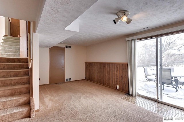 basement with ceiling fan, light carpet, and a textured ceiling