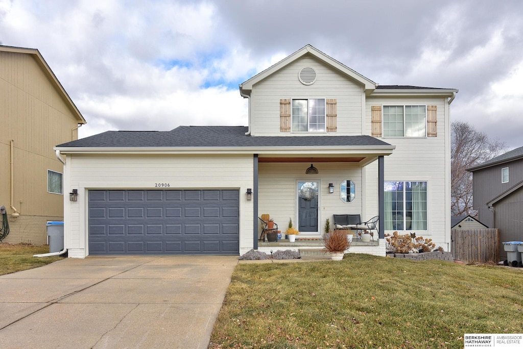 view of front of home with a garage, a front lawn, and covered porch