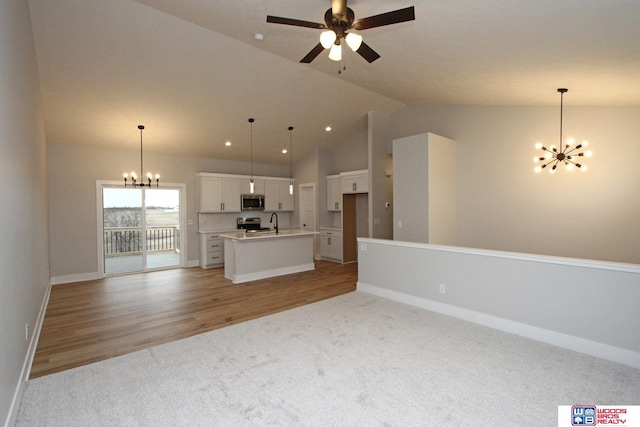 unfurnished living room featuring ceiling fan with notable chandelier, sink, light colored carpet, and high vaulted ceiling