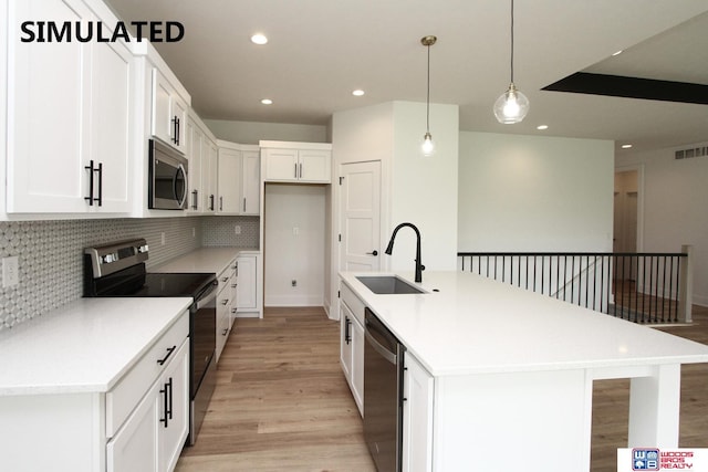 kitchen with sink, hanging light fixtures, a center island with sink, appliances with stainless steel finishes, and white cabinets