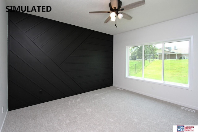 carpeted spare room with ceiling fan and wooden walls