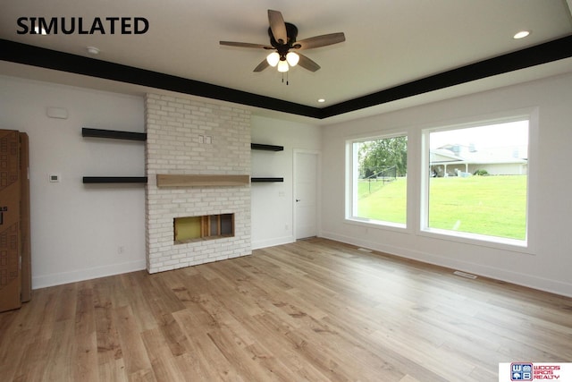 unfurnished living room featuring a fireplace, light hardwood / wood-style floors, and ceiling fan