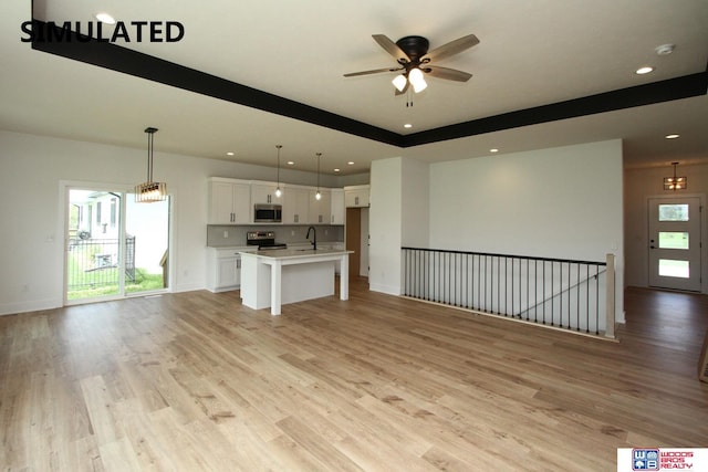 unfurnished living room featuring ceiling fan, sink, and light wood-type flooring