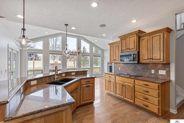 kitchen featuring pendant lighting, sink, light hardwood / wood-style flooring, black electric cooktop, and vaulted ceiling