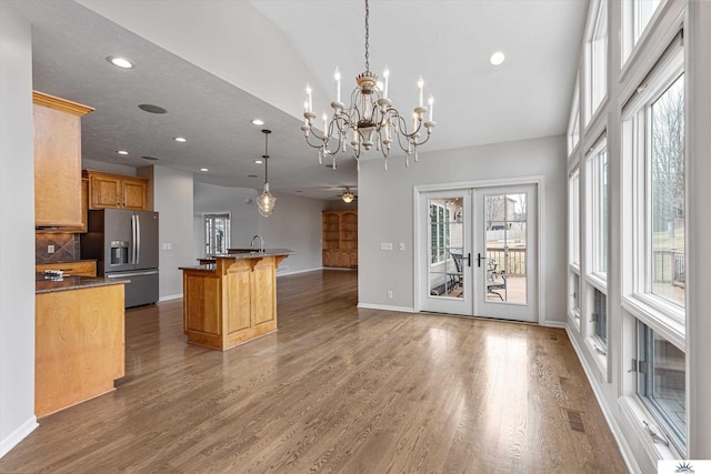 kitchen with an island with sink, a kitchen breakfast bar, decorative light fixtures, and stainless steel fridge with ice dispenser