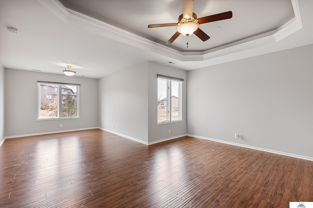 empty room with crown molding, ceiling fan, dark hardwood / wood-style flooring, and a tray ceiling