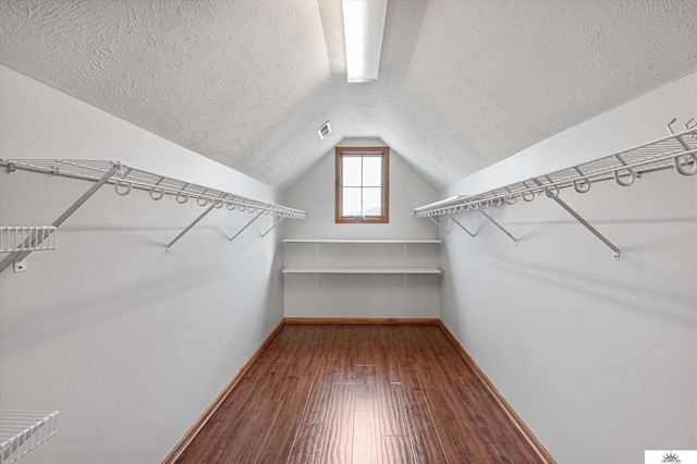 walk in closet featuring hardwood / wood-style flooring and vaulted ceiling