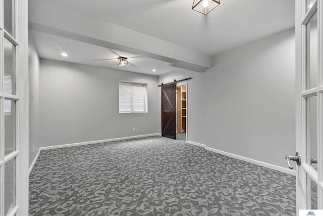 empty room featuring dark carpet and a barn door