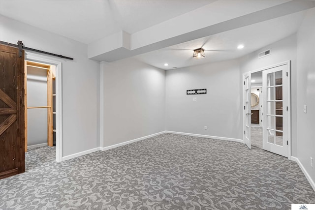 carpeted empty room with a barn door