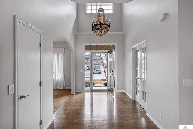 entryway featuring french doors, dark hardwood / wood-style floors, a chandelier, and a high ceiling