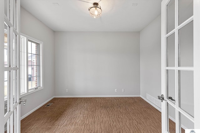 carpeted spare room featuring french doors