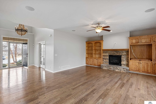 unfurnished living room with hardwood / wood-style floors, ceiling fan with notable chandelier, and a fireplace