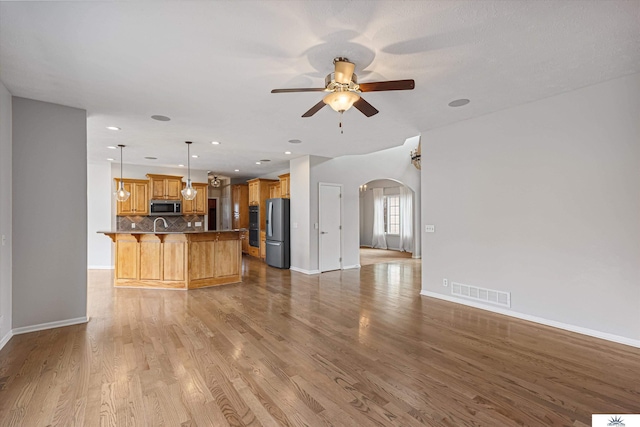 unfurnished living room featuring ceiling fan and light hardwood / wood-style flooring