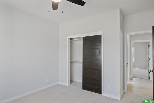 unfurnished bedroom featuring ceiling fan, light colored carpet, and a closet