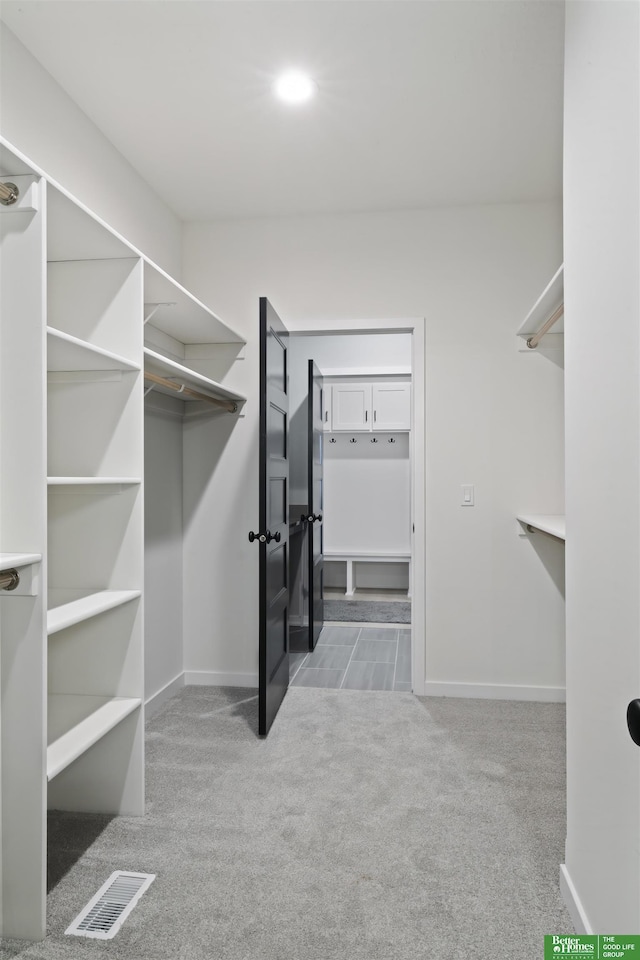 walk in closet featuring light carpet