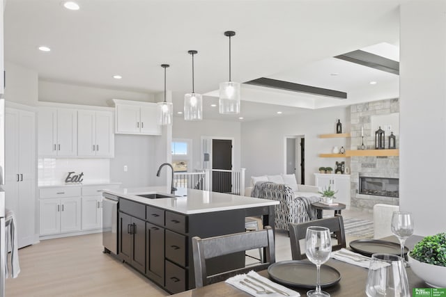 kitchen with white cabinetry, dishwasher, sink, and a center island with sink