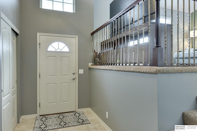 foyer entrance featuring light tile patterned floors and a towering ceiling