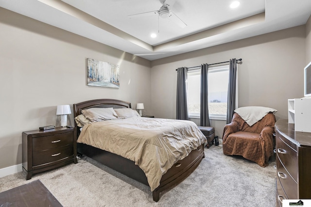 bedroom featuring light colored carpet, a raised ceiling, and ceiling fan