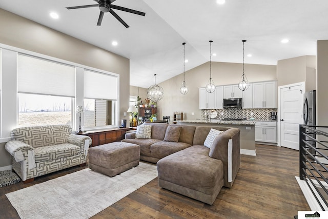 living room with dark hardwood / wood-style flooring, ceiling fan with notable chandelier, and high vaulted ceiling